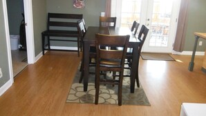 Un coin repas avec une table et des chaises, un tapis et un tableau au mur.