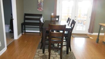 Un coin repas avec une table et des chaises, un tapis et un tableau au mur.