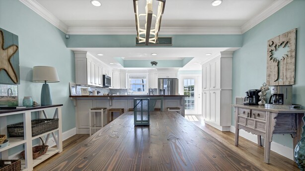 A spacious kitchen with white cabinets, a central island, and a view to the outside. - Magnificent 6br/6bth home w/ IN-GROUND HEATED POOL & Luggage Lift! (Edisto Island)