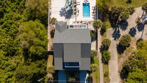An aerial view of a house with a swimming pool, surrounded by trees and a well-maintained lawn. - Magnificent 6br/6bth home w/ IN-GROUND HEATED POOL & Luggage Lift! (Edisto Island)