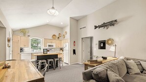 A modern kitchen with a dining area, a sofa, and a wall-mounted fish decoration. - Park Place - 20 Miles to YNP ~ Hot Tub ~ Wi-Fi ~ Fire Pit (Island Park)