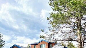 A two-story house with a garage, a covered porch, and a gravel driveway. - Park Place - 20 Miles to YNP ~ Hot Tub ~ Wi-Fi ~ Fire Pit (Island Park)