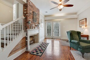 Cozy living space with a brick fireplace, hardwood floor, and comfortable seating area.