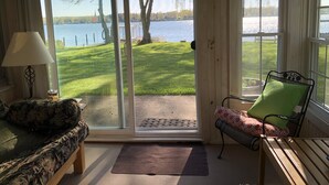 Ein Zimmer mit Blick auf einen See, eine Couch, ein Sessel und eine Lampe.