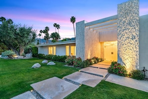 A modern house with a stone facade, a well-manicured lawn, and a pathway leading to the entrance. - NEW! Private Wellness Resort! Pool, Spa, Cold Plunge & Cabanas Indian Canyons PS (Palm Springs)