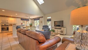 A spacious living area with a leather sofa, a television, and a dining table.