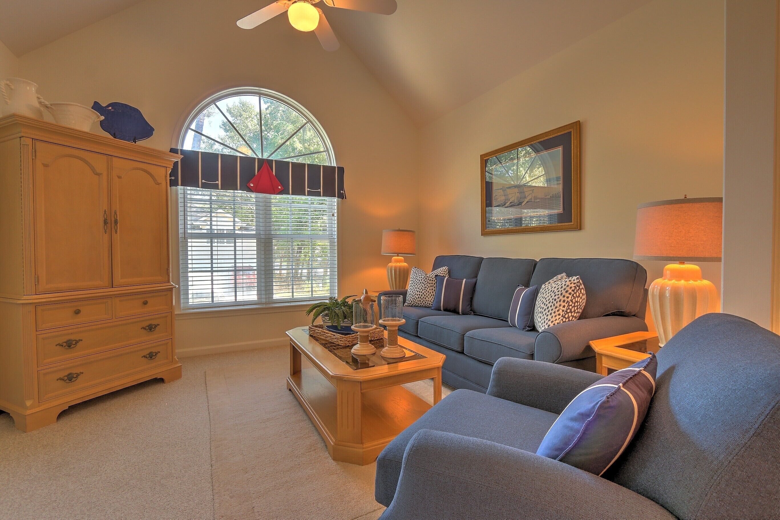 A living room with a sofa, a coffee table, a cabinet, and a window with blinds.
