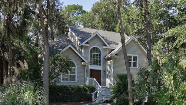 A two-story house with a front porch, a staircase, and a pathway leading to the entrance.