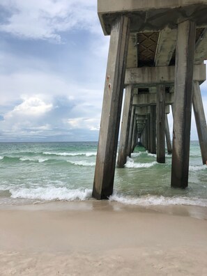 A concrete pier extending into the ocean with waves crashing against it.