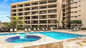 A multi-story hotel with a swimming pool, lounge chairs, and palm trees. - Squeaky clean groundfloor Sugar Beach #104 (Kihei)