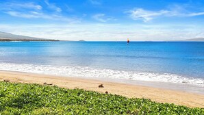 A beach with a clear sky, calm sea, and distant sailboat. - Squeaky clean groundfloor Sugar Beach #104 (Kihei)