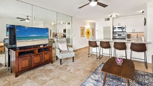 A modern living room with a TV, seating, a dining area, and a kitchen. - Squeaky clean groundfloor Sugar Beach #104 (Kihei)
