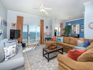 Relax in this inviting living room with a large flat-screen TV, comfortable seating area, and balcony with ocean views.