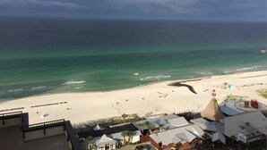 A beach view with a sandy shore, a few umbrellas, and a building with a conical roof.