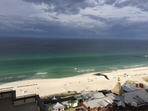 A beach view with a sandy shore, a few umbrellas, and a building with a conical roof.