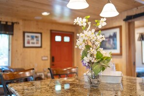 Ein Essbereich mit einem Granittisch, Stühlen, einer Vase mit Blumen und einer Holztür im Hintergrund.