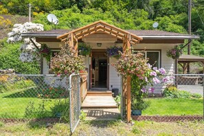 Ein Haus mit einer Holzveranda, einer Satellitenschüssel und einem blühenden Garten.