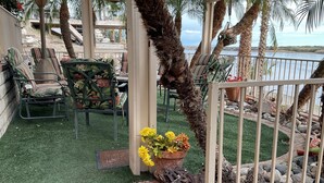 A patio area with outdoor furniture, a decorative plant, and a view of the sea.