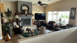 A living room with a stone fireplace, a television, and comfortable seating.
