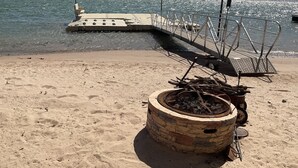 A sandy beach with a stone planter and a metal grill.
