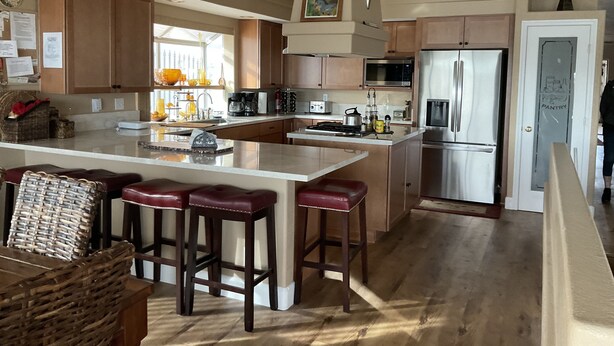 A modern kitchen with a central island, stainless steel appliances, and wooden cabinetry.