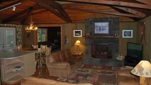 Una sala de estar acogedora con chimenea, vigas de madera, un sofá, una mesa de centro y un televisor.
