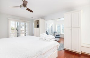 Un dormitorio con cama, ventilador de techo, armario y vistas al exterior.
