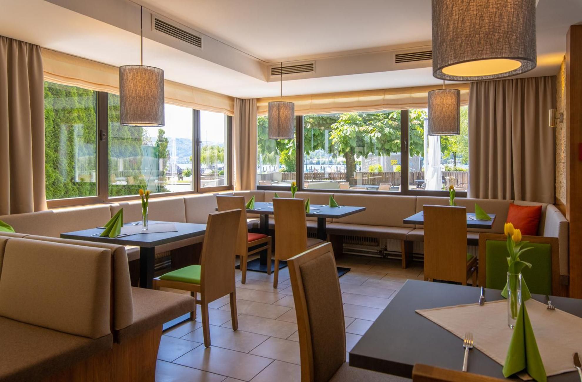 A restaurant interior with seating arrangements, large windows, and hanging lamps.