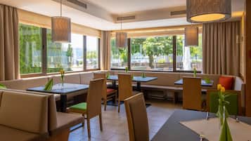 A restaurant interior with seating arrangements, large windows, and hanging lamps.