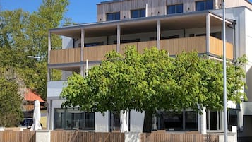 Ein mehrstöckiges Wohngebäude mit Balkonen, großen Fenstern und einem Baum im Vordergrund.