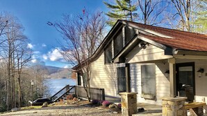 Une maison avec un porche en pierre, un escalier en bois et une vue sur un lac.