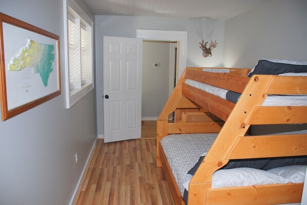 A room with a bunk bed, a framed map on the wall, and a door leading to another room. - Splendor Cove Retreat…Lakefront w/ dock, Huge Yard, Lake Toys, Stream w/ wfall (Cullowhee)