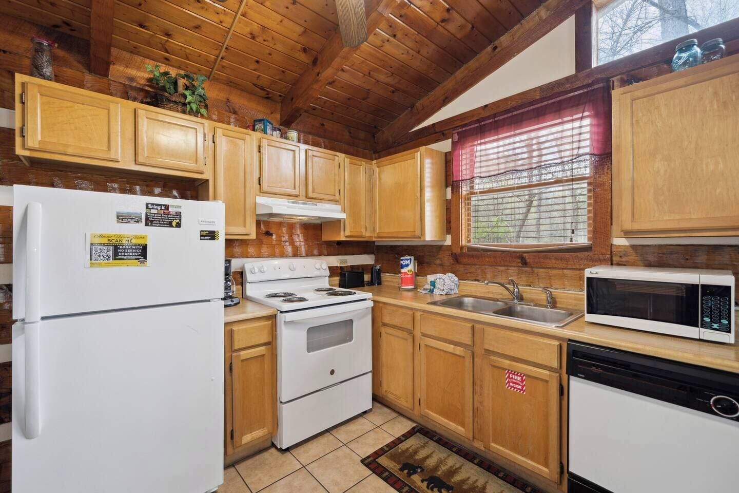 A compact kitchen with wooden cabinets, a refrigerator, stove, sink, and microwave.