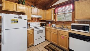 Una cocina compacta con armarios de madera, refrigerador, estufa, lavaplatos y microondas.