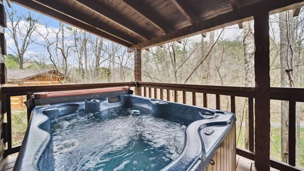 Un jacuzzi en una terraza de madera con vistas a árboles.