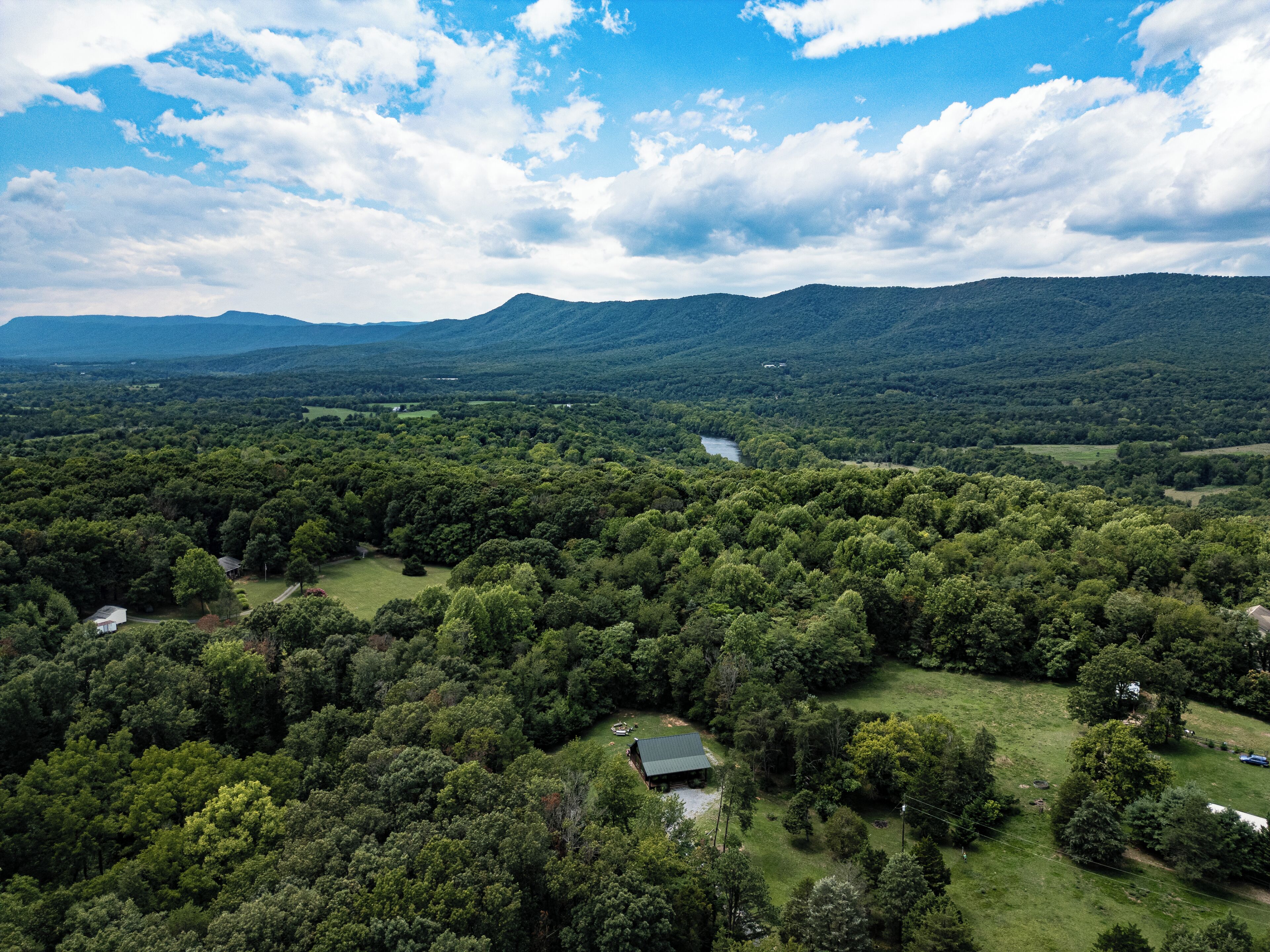 Vista panorámica de un paisaje verde exuberante con un río, colinas y edificios dispersos.
