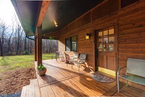 Een houten chalet met een veranda, buitenmeubels en uitzicht op het omliggende bos.