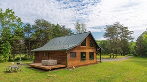 Een houten chalet met een terras, buitenmeubels en een overdekte patio.