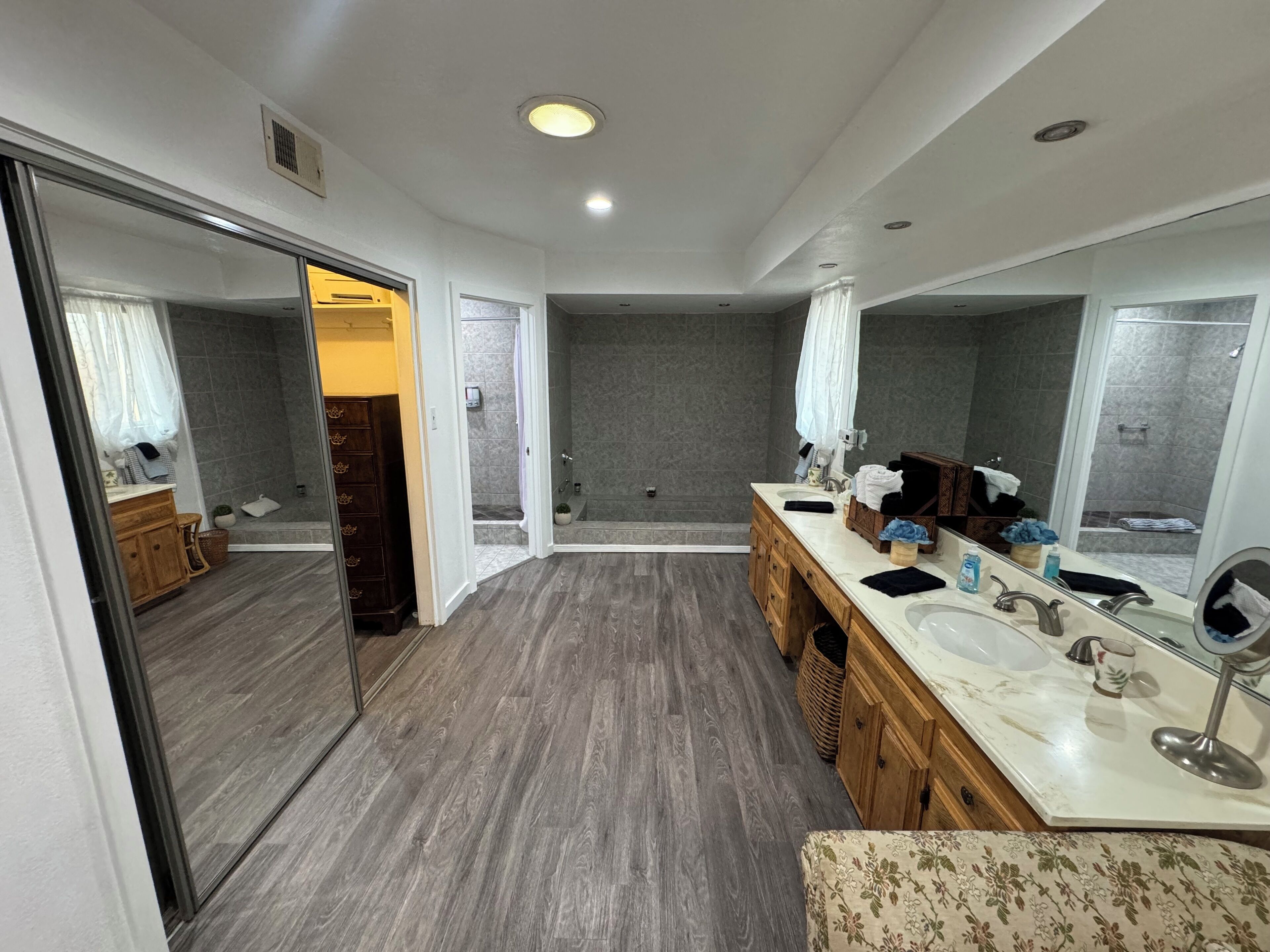 A modern bathroom with a large mirror, dual sinks, and a shower area.