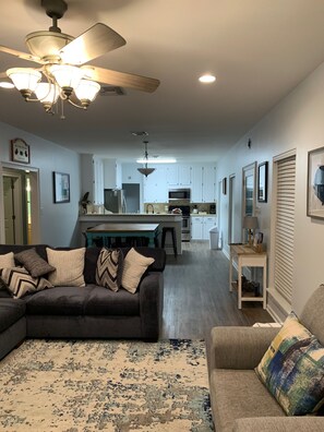 A modern living room with a dark sofa, a patterned rug, and a ceiling fan. - Seafood and fishing time. Book your fishing trip catch specks and reds. (Chauvin)