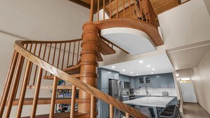 A wooden spiral staircase leading to a modern kitchen with a central island and bar seating. - Summer DEALS-A/C-Pool-Oceanview Building 1 ! (Kihei)