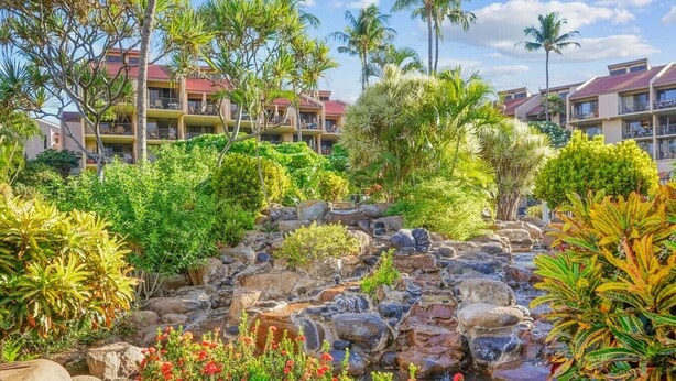 A resort with a landscaped garden featuring a rock waterfall, palm trees, and tropical plants. - Summer DEALS-A/C-Pool-Oceanview Building 1 ! (Kihei)