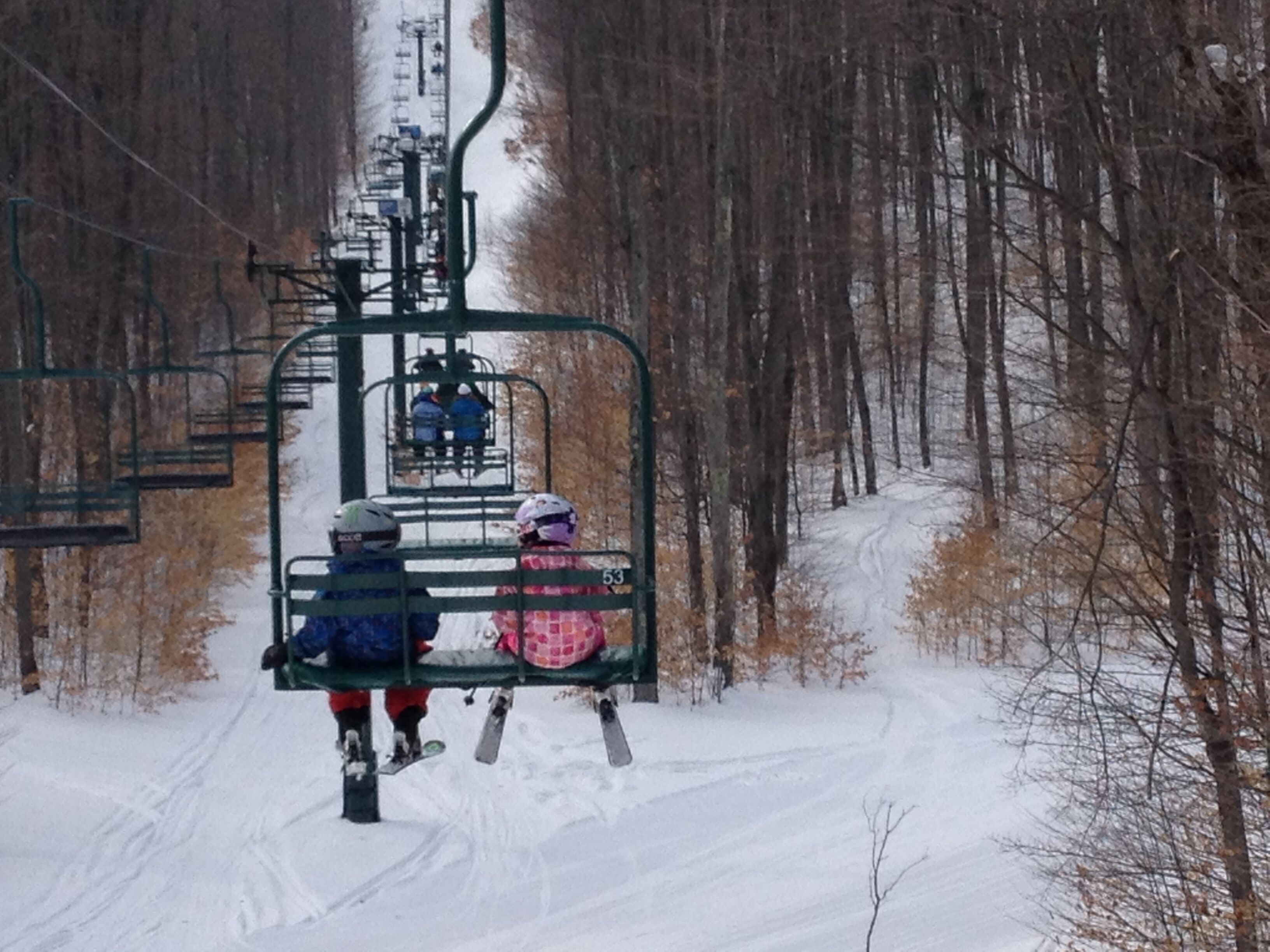 A ski lift with two skiers descending.
