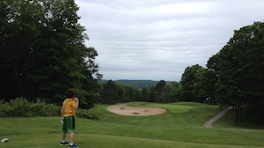 A golf course with a putting green, sand bunkers, and a path leading to a tee box.