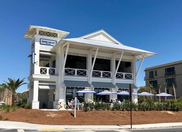 A building with a sign reading "SHUNK GULLEY" and a covered outdoor seating area with umbrellas.