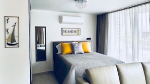A modern hotel room with a bed, a sofa, a mirror, and a sign that reads "SEASIDE". - Convenient Location in Condado! (Santurce)