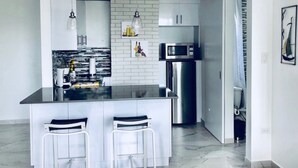 A modern kitchen with a central island, white cabinets, a stainless steel refrigerator, and a microwave. - Convenient Location in Condado! (Santurce)