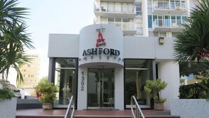 The Ashford hotel entrance with a modern design, featuring a prominent logo, a staircase with metal railings, and a glass door. - Convenient Location in Condado! (Santurce)