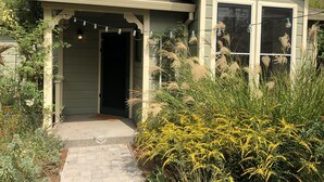 A house with a covered porch, a front door, and a garden with various plants.
