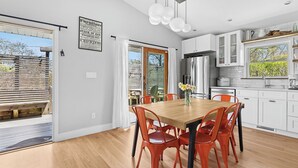 A modern kitchen with white cabinets, a wooden dining table, and orange chairs. - PRICE REDUCED Family Friendly, 3Bd Centrally Located Home with Fenced in Yard (Montauk)